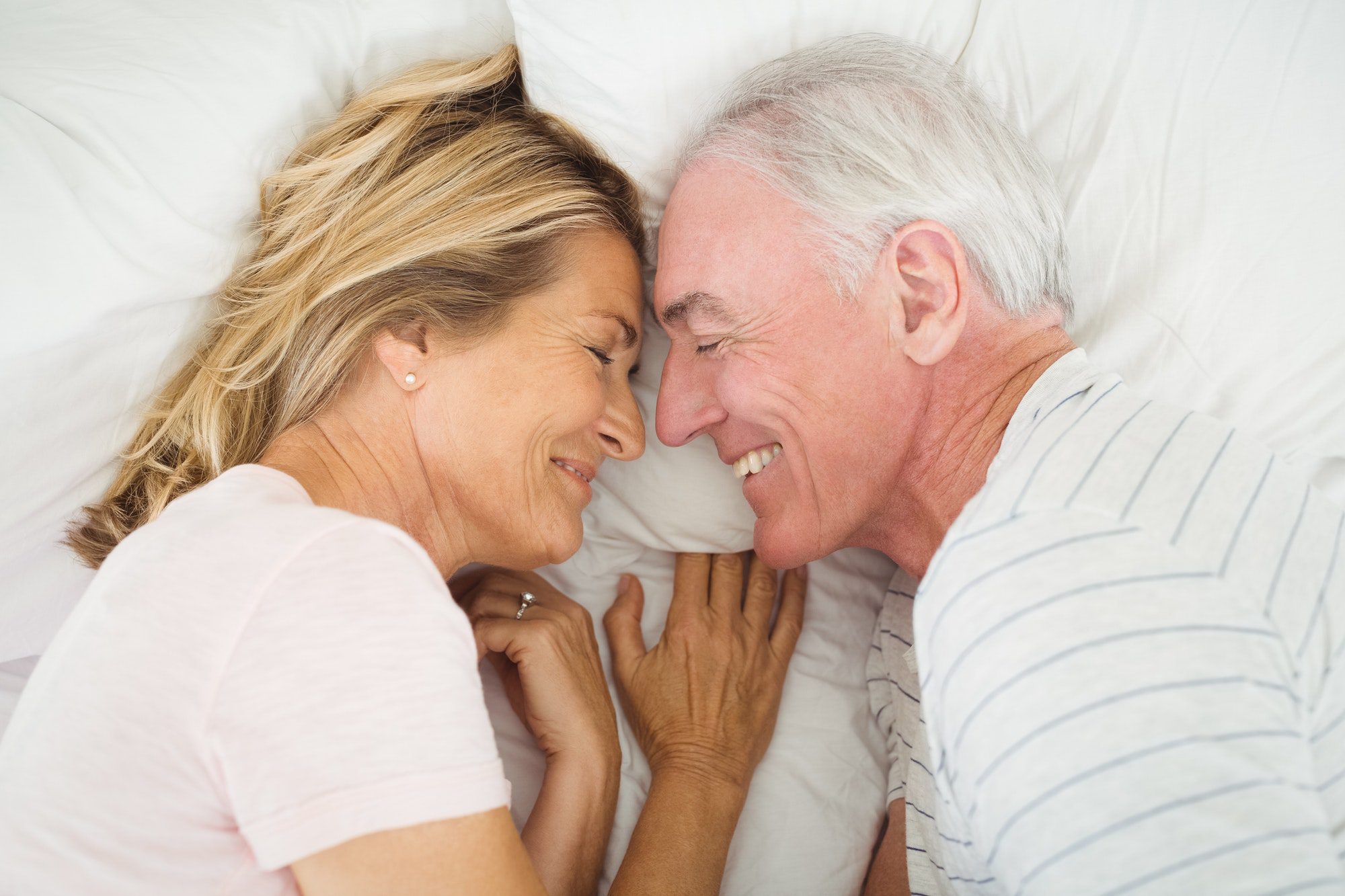 Happy senior couple laying in bed discussing their medicare options for Texas.