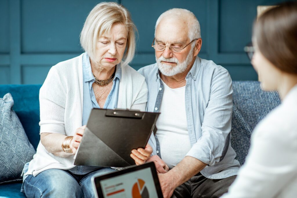 Senior couple with consultant at the office Delayed Medicare Enrollment