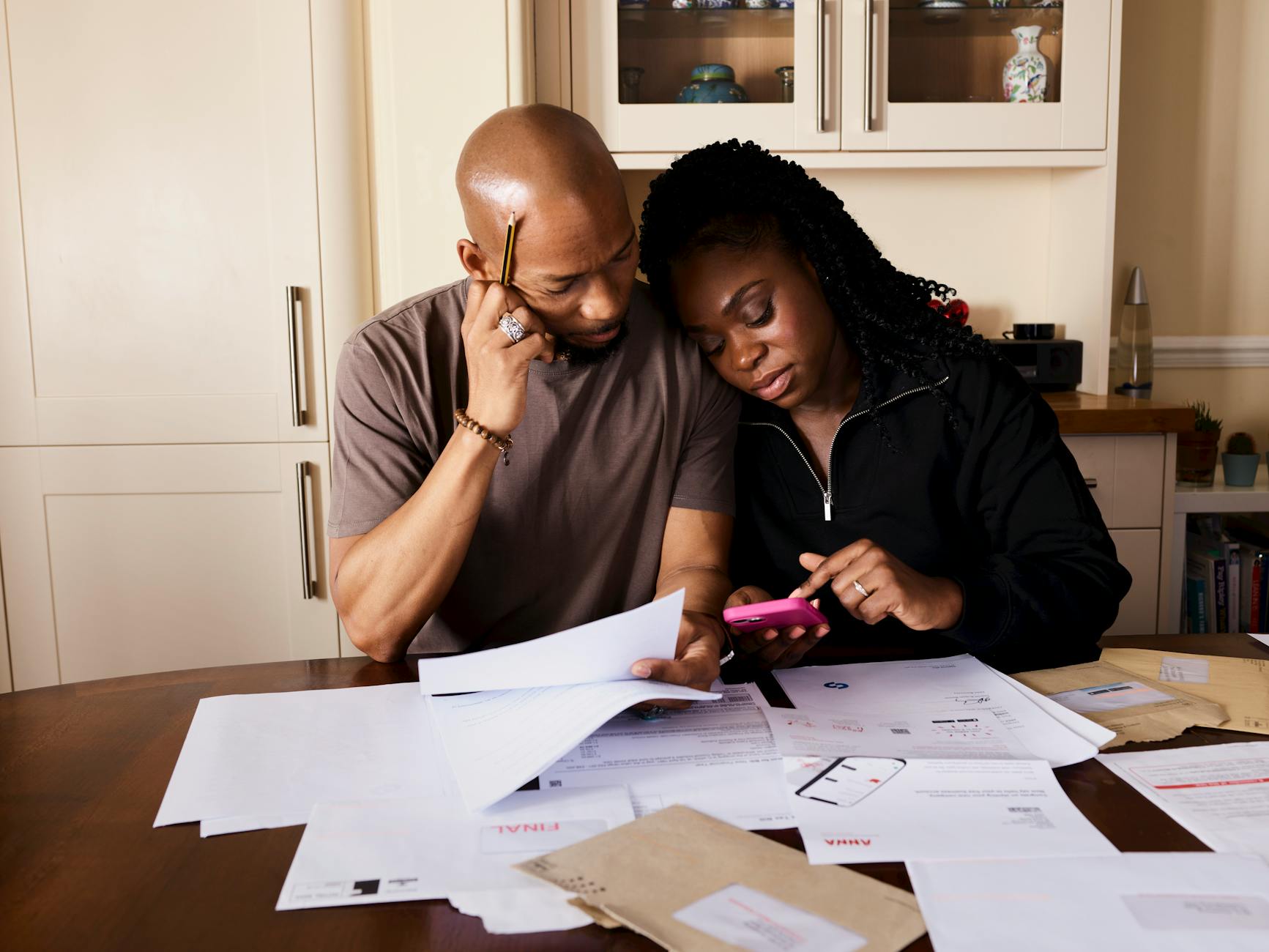 Houston couple in their early 60s sitting at the kitchen table reviewing health insurance paperwork while planning their bridge from ACA Marketplace coverage to Medicare at 65.