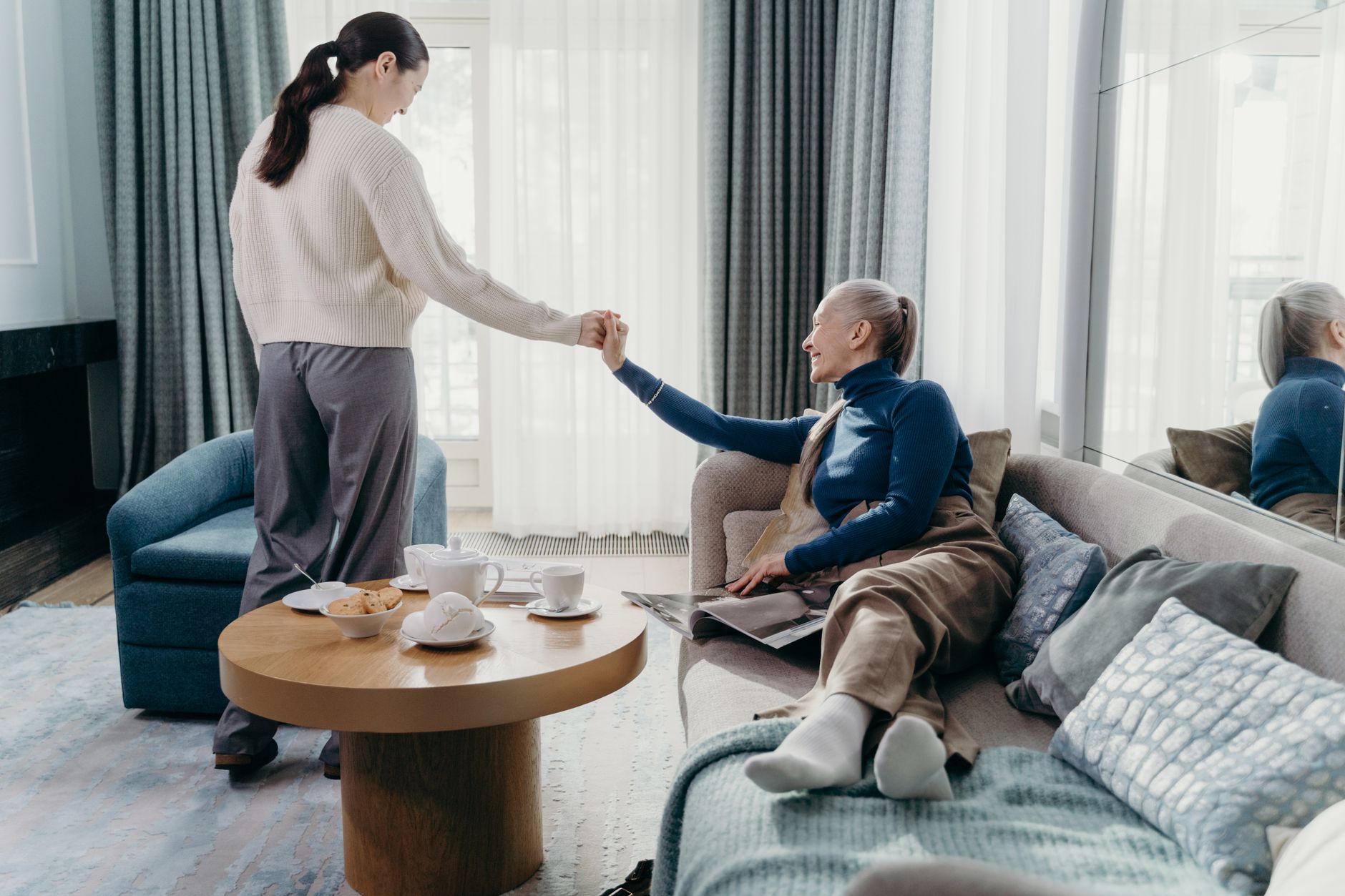 Houston family caregiver holding hands with an elderly parent living with dementia in a home living room